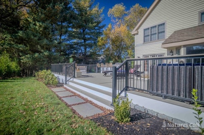 Drone view straight down on the Chadds Ford home and back patio: the composite deck wraps around the back of the tan-siding house with the outdoor kitchen, hot tub, and fire pit zones laid out in a single readable plan