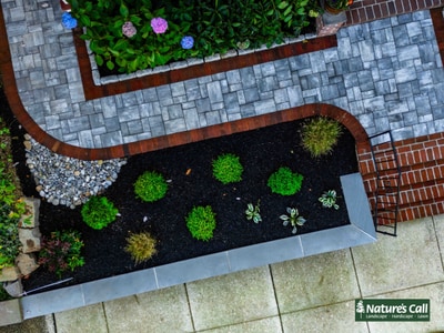 Hardscape design with ornamental grasses, perennials, and paver patio accents in blue and rust tones in Wilmington, Delaware.